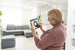 technology, automation and efficiency concept - smiling senior woman in glasses with tablet computer using smart home app over grey background