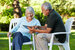 Two senior people sitting with a tablet PC, outside in a senior living community