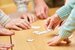 Hand of a senior citizen holds a piece of the puzzle while playing a puzzle in a retirement home