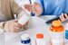 Close up hands of a senior woman holding a medical bottle and asking information from the medication aide before administering medication