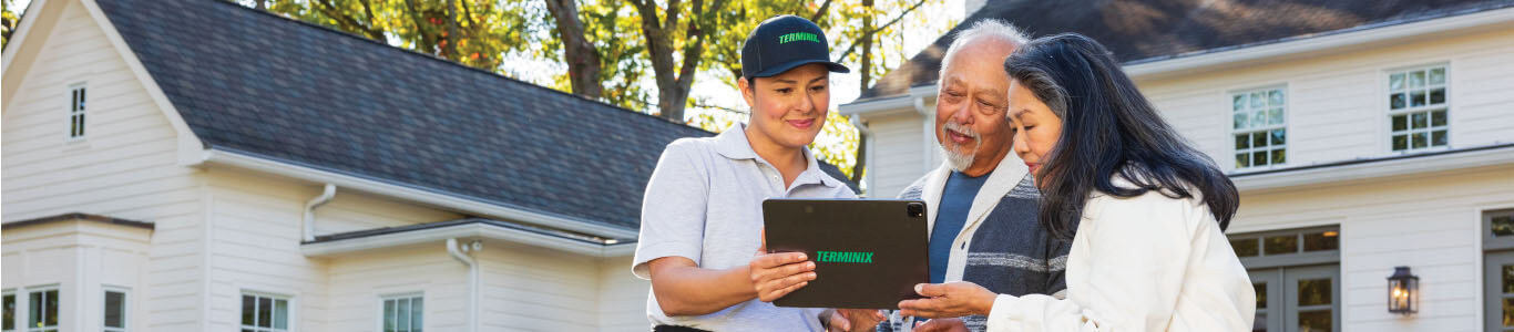 Terminix technician sharing a report with customers in front of their house