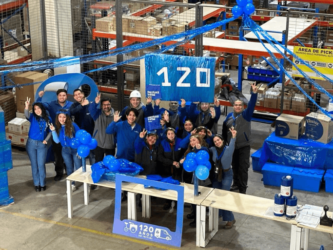 Employees celebrating Initial's 120th anniversary at a warehouse with Initial blue signage