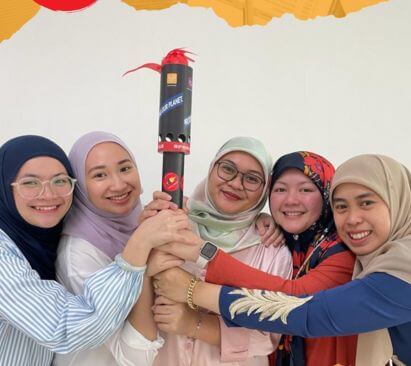Female employees from Brunei holding a torch