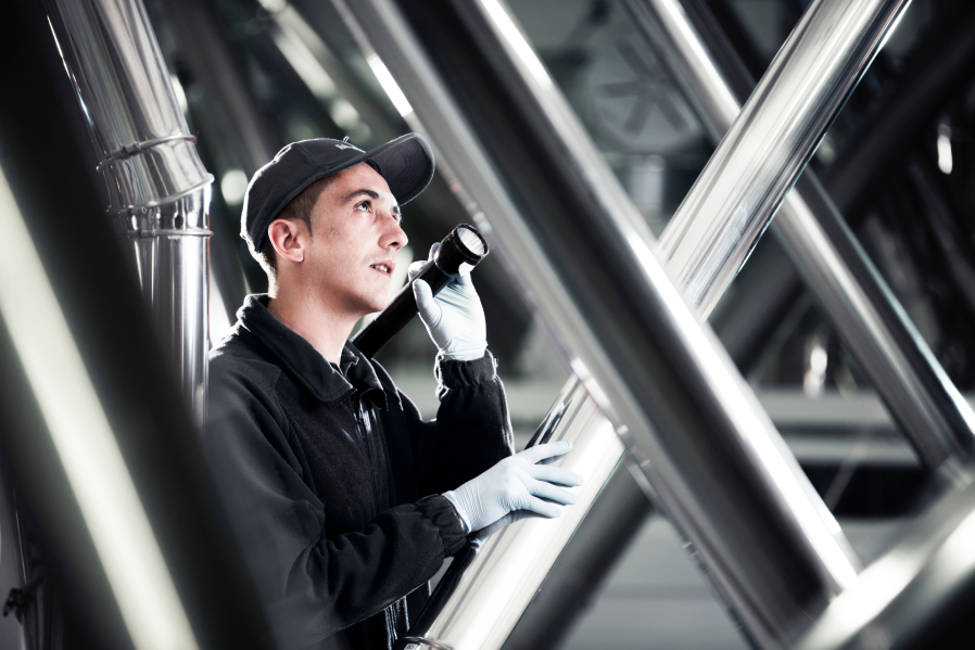 Pest technician inspecting tubes in a factory