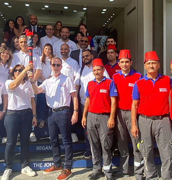 The managing director holding a torch with other employees on a building's entry staircase