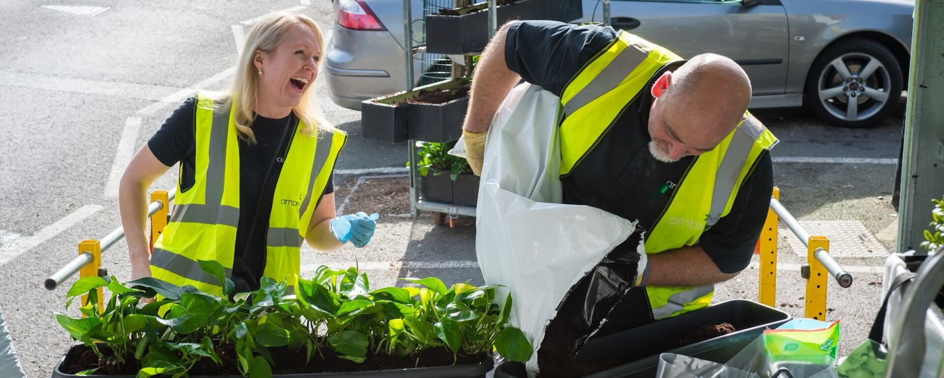 Ambius technicians laughing while filling planters with soil