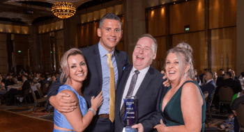 Colleagues hugging and smiling at an awards party