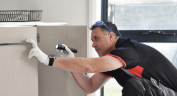 Pest technician kneeling down to service kitchen