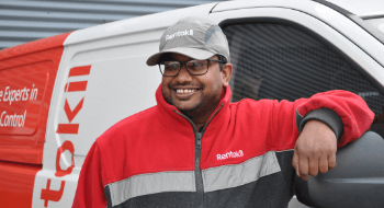 Pest technician leaning on his van