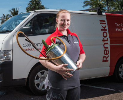 Pest technician holding a sprayer tank in front of a van