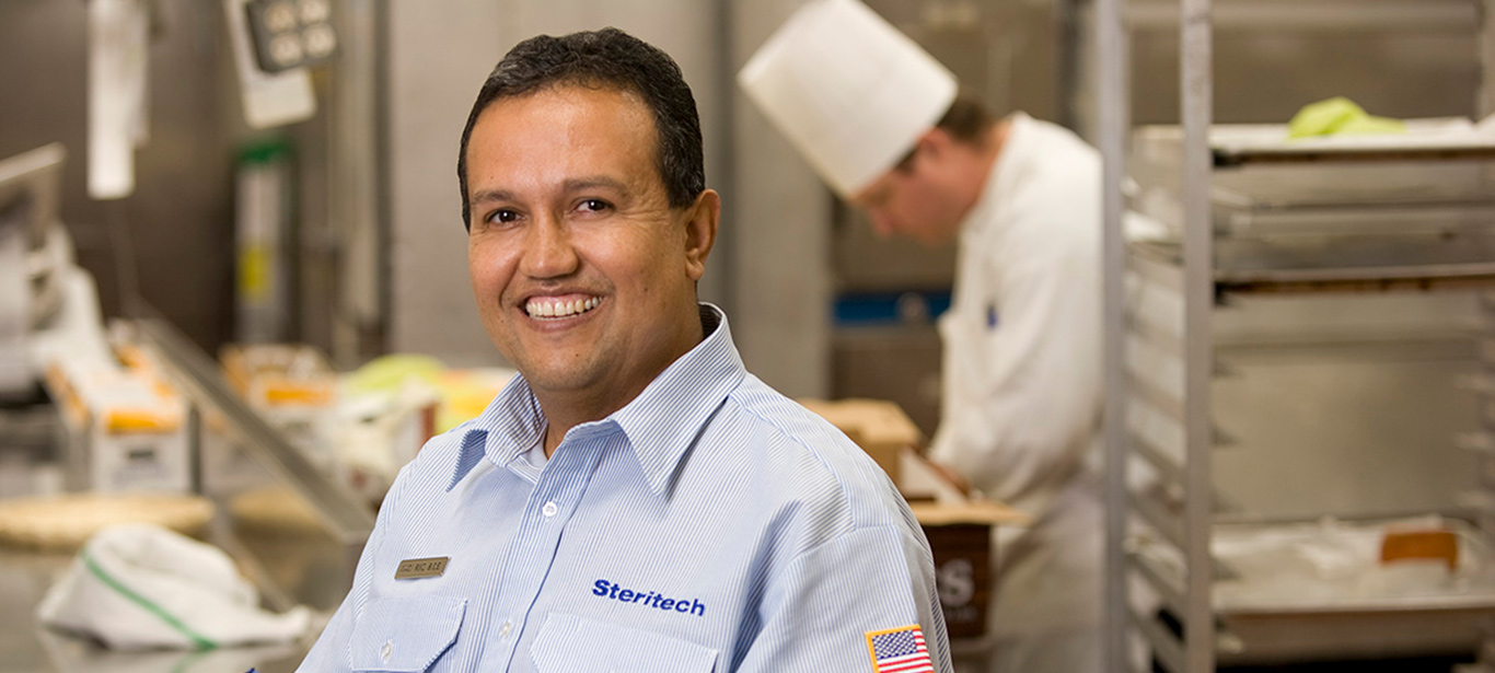 Steritech technician in kitchen using handheld device