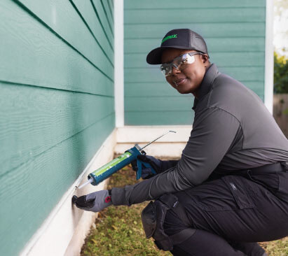 Terminix technician sealing the outside of a house