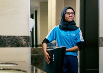 Initial technician carrying Signature feminine hygiene unit out of a washroom