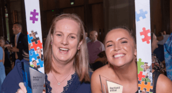 Two colleagues posing inside a frame at an awards party