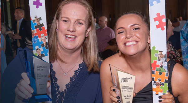 Two colleagues posing inside a frame at an awards party