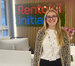 A picture of Sarah Lane, a young white female with blonde hair, in her early twenties smiling in front of the Rentokil Initial Logo