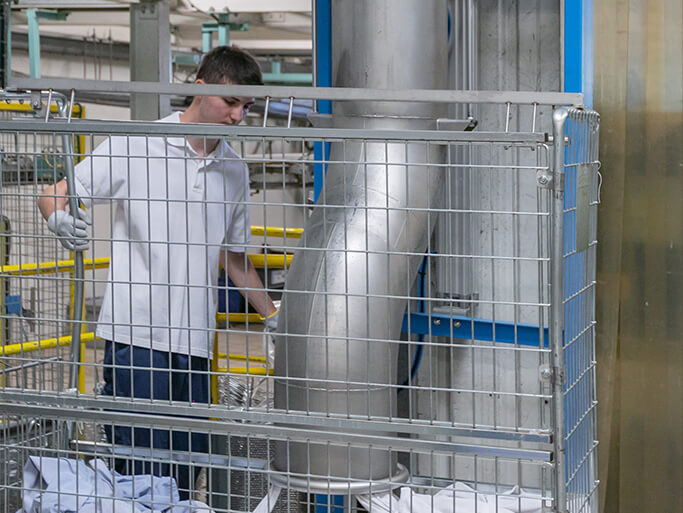 Technicien Initial Textile transportant un chariot de vêtements dans une blanchisserie