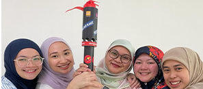 Female employees from Brunei holding a torch