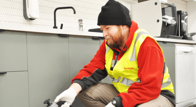 Pest technician kneeling down to service kitchen