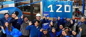 Employees celebrating Initial's 120th annievrsary at a warehouse with Initial blue signage