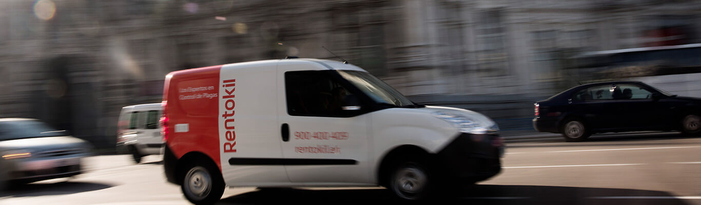 Ein Lieferwagen von Rentokil, der sich mit hoher Geschwindigkeit auf einer belebten Stadtstraße bewegt. Das Bild ist verschwommen.