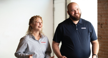 Two smiling Terminix employees walk down a hallway and talk.