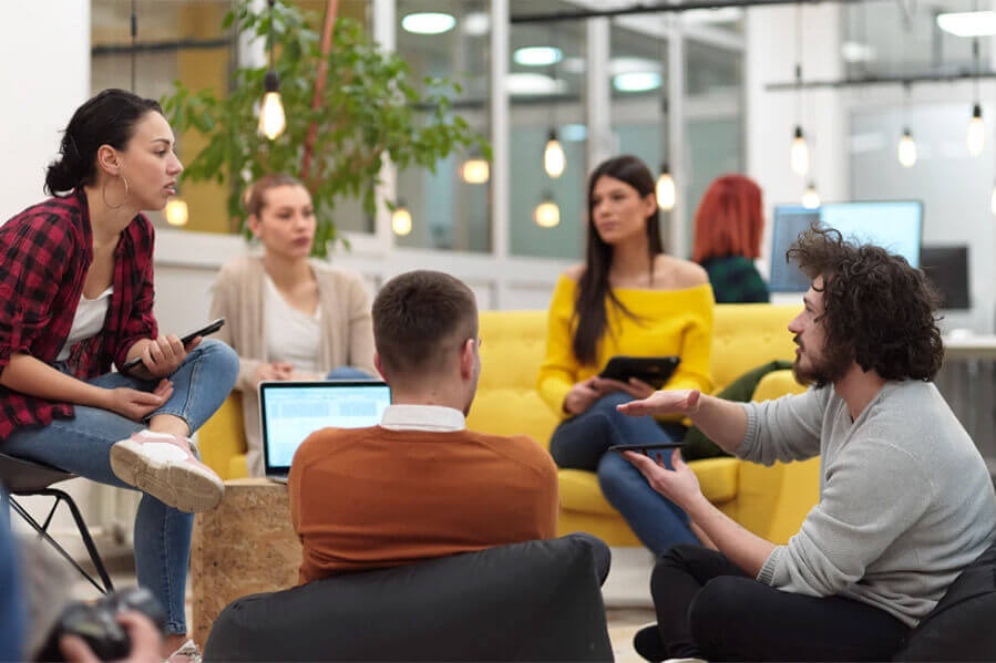 Gruppe junger Leute sitzt in einem modernen Büro und bespricht Ideen.