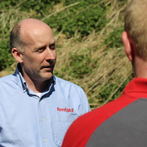 Alt text: A balding man in a blue **Rentokil** shirt talks to another person with their back to the camera.