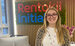 A picture of Sarah Lane, a young white female with blonde hair, in her early twenties smiling in front of the Rentokil Initial Logo