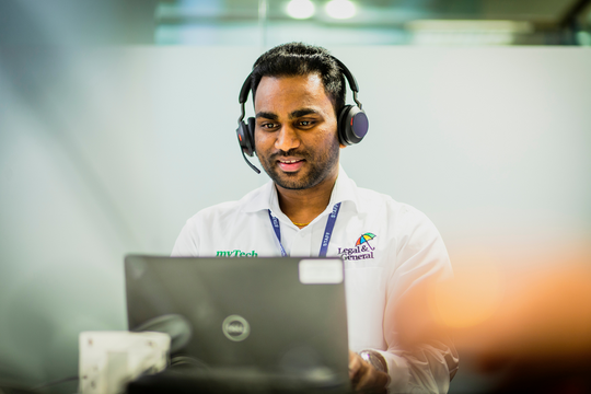 man sat at a laptop with a headset on