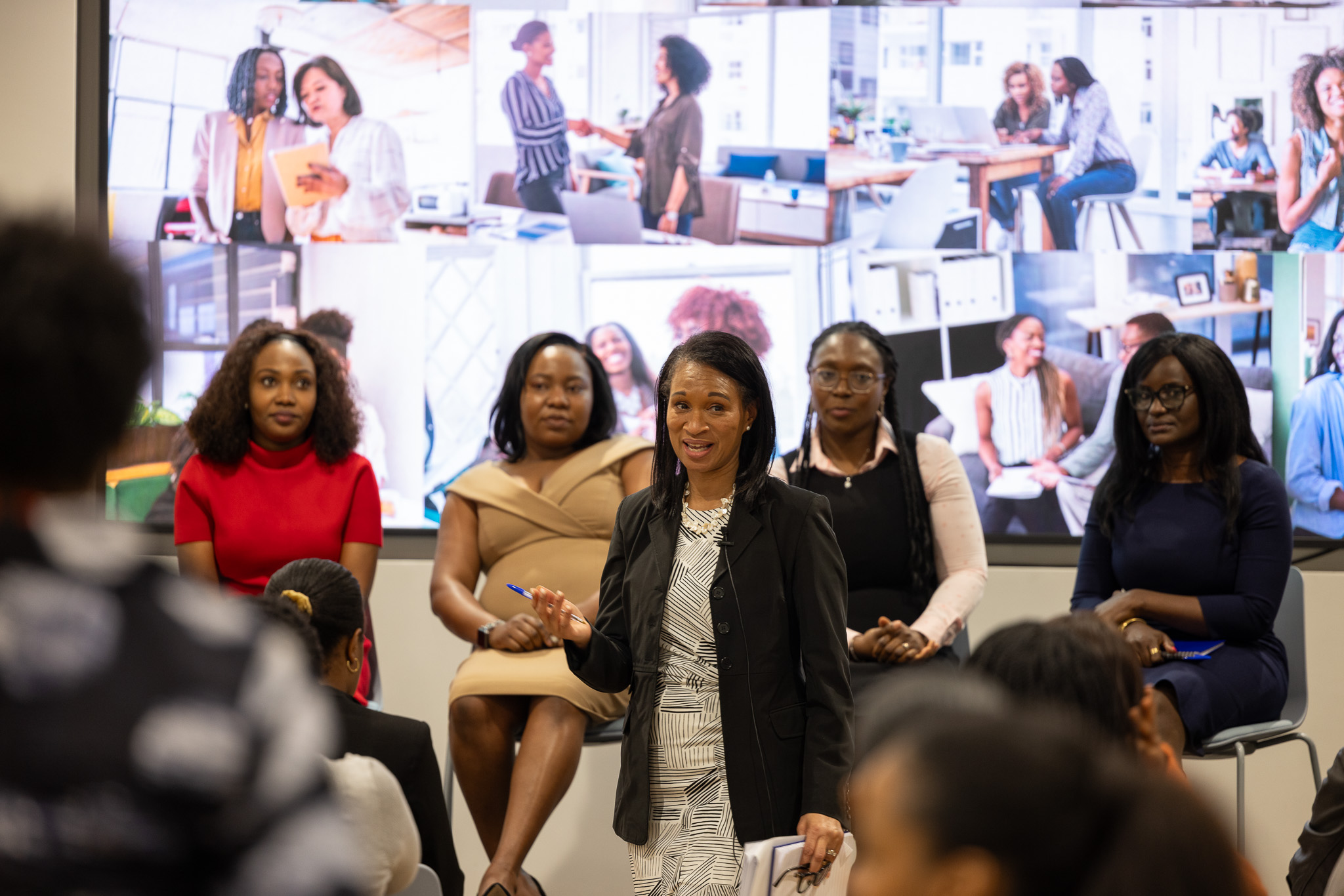 group of women sitting in a line with a keynote speaker stood in front