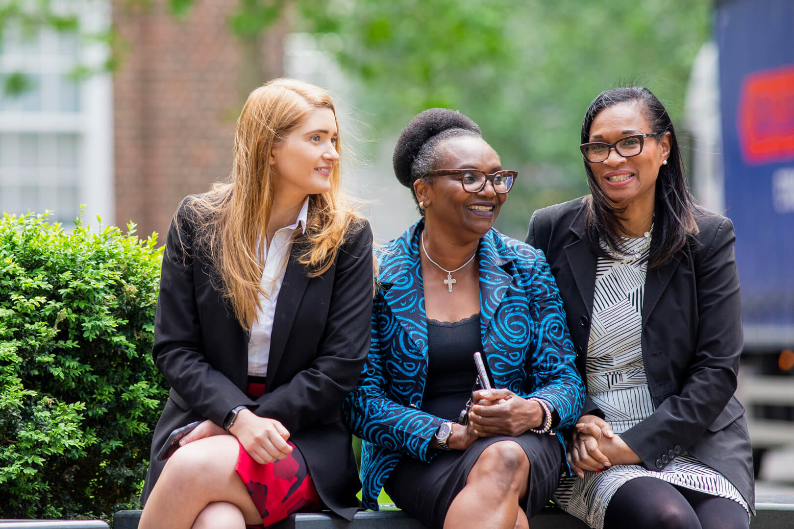 three professional women sitting on a bench and smiling - finance careers london