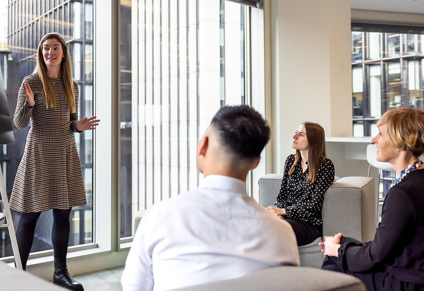 woman presenting and three people listening