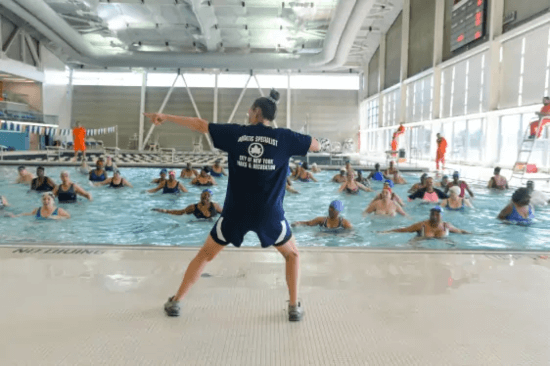  Synchronized swim class at a NYC Parks & Recreation pool. Instructor's shirt reads "Aquatic Specialist, City of New York, Parks & Recreation."