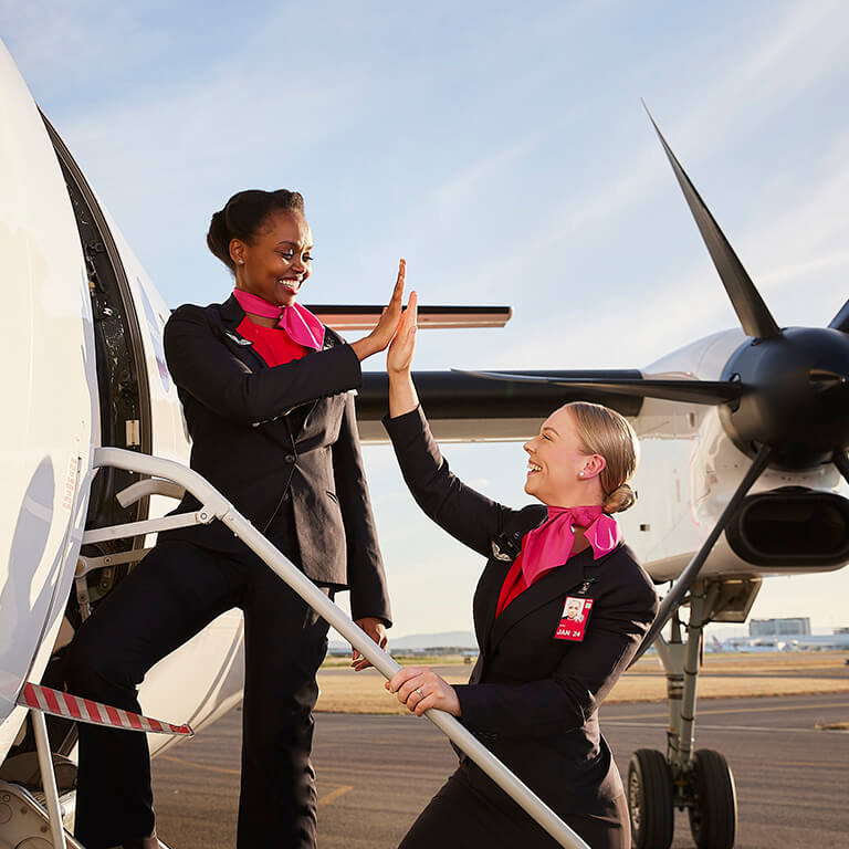 Two members of our cabin crew team on the airstairs, hi-fiving