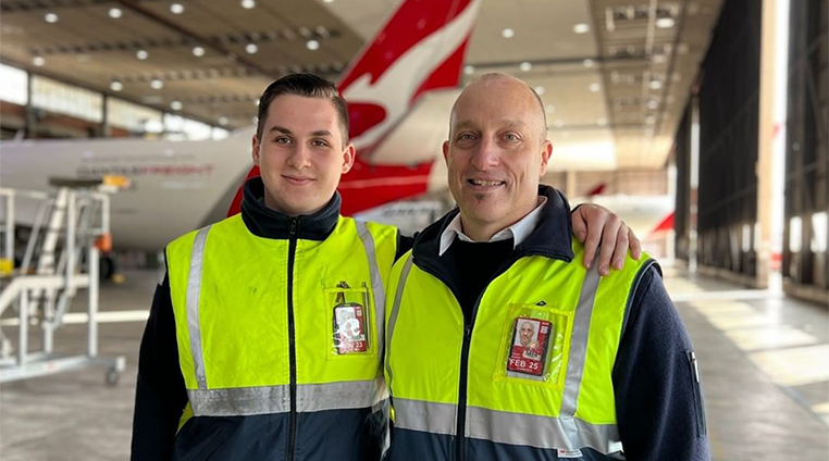 Father and son engineers with arms around each other, smiling