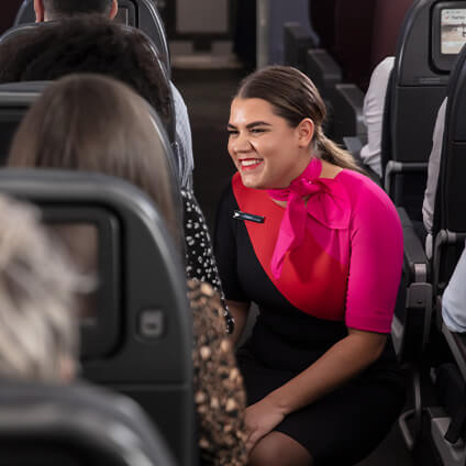 First Nations Cabin Crew member engaging in a friendly conversation with a customer onboard