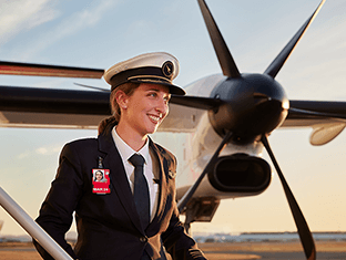 Smiling Qantas pilot looking off the the side, plane propellers in background