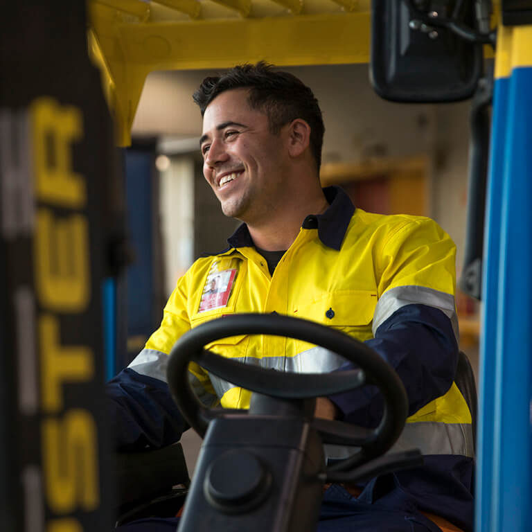 A member of our Freight team sitting on a ground-vehicle smiling