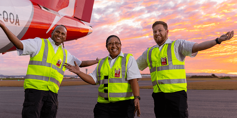 Members of Qantas engineering team on the tarmac with a beautiful sunset in background