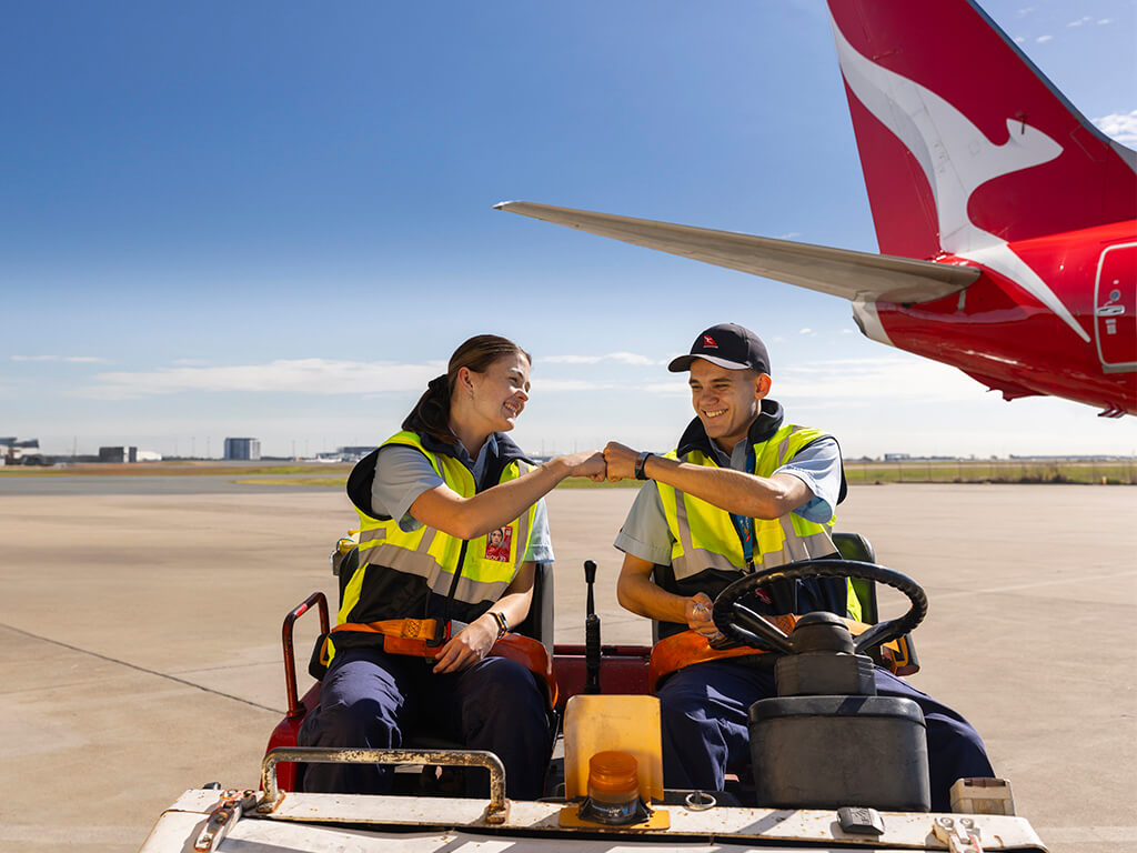 Two engineering apprentices on the tarmac, bumping fists