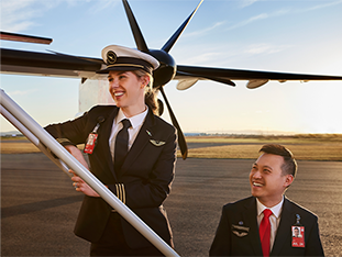 Two QantasLink pilots standing on the stairs up to the door of the plane, smiling