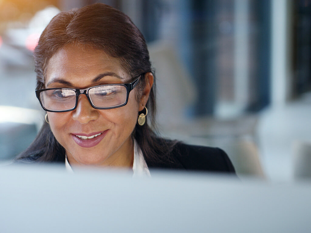 Qantas employee smiling while working at a computer, looking engaged in their work environment