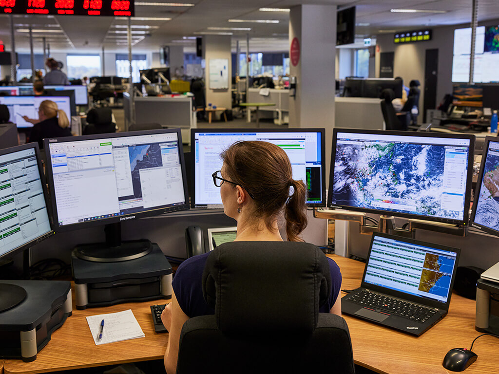 Qantas Meteorologist reviewing weather conditions on multiple screens, demonstrating analytical expertise in weather forecasting