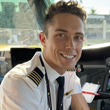 A QantasLink First Officer in the cockpit, smiling