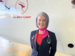 Cabin crew member standing in front of a plane, smiling 