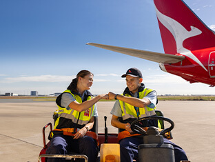 Two engineering apprentices on the tarmac, bumping fists