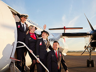 A combination of cabin crew and pilots on the airstairs all smiling and laughing