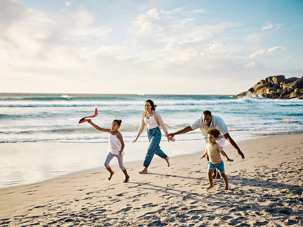 A family running down a beach with a Qantas plane toy