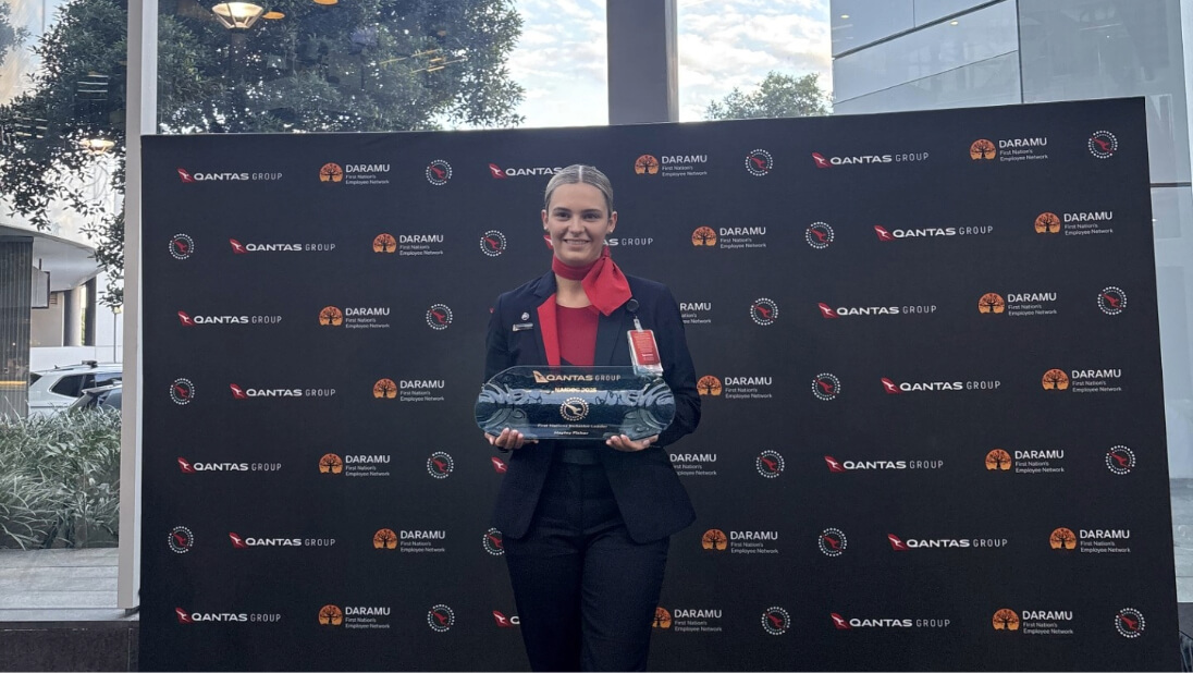 Qantas employee holding an award and smiling at camera